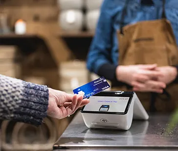 Nahaufnahme einer kontaktlosen Kartenzahlung an einem modernen Kassenterminal auf einer Café-Theke.