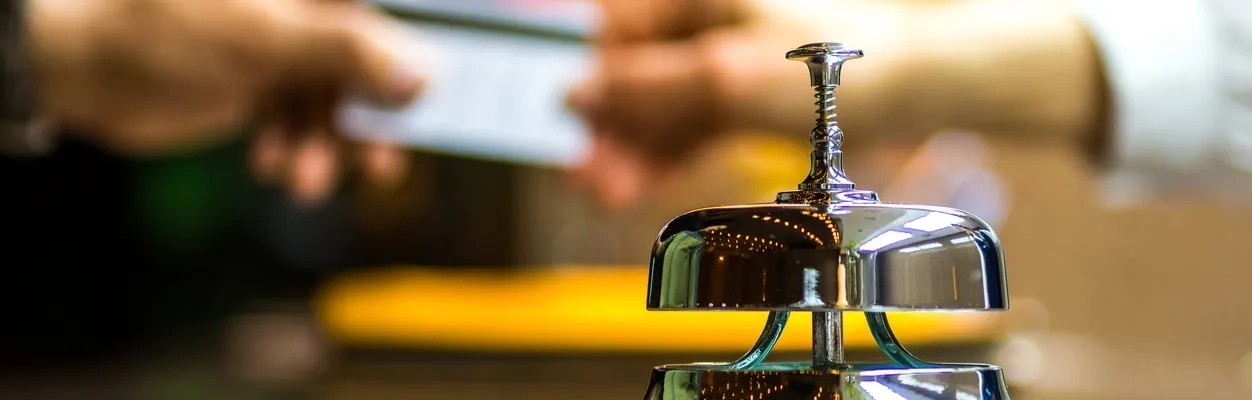 Hotelrezeption mit einer Serviceklingel und einer Person, die eine Karte übergibt.