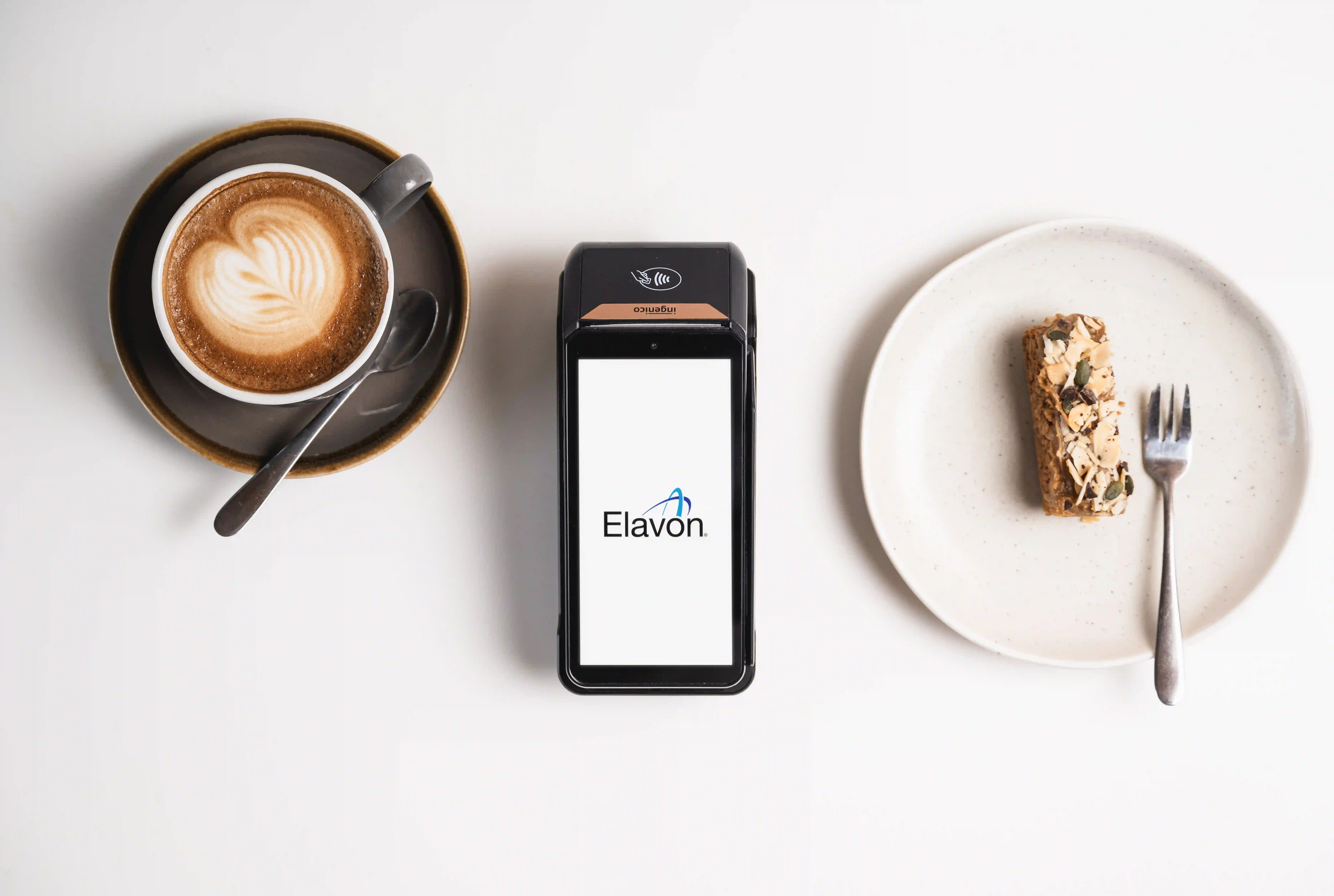 Kaffeetasse, elavon zahlungsterminal und gebäck auf tisch im café