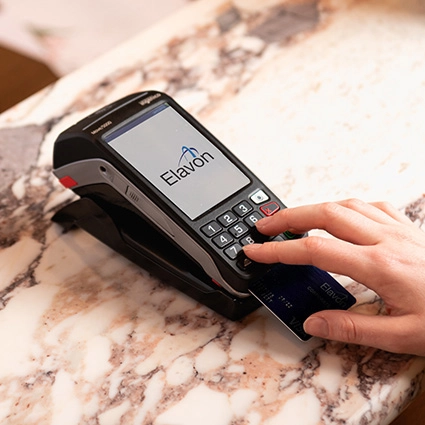 Hand steckt eine kreditkarte in ein zahlungsterminal auf einer marmorarbeitsplatte