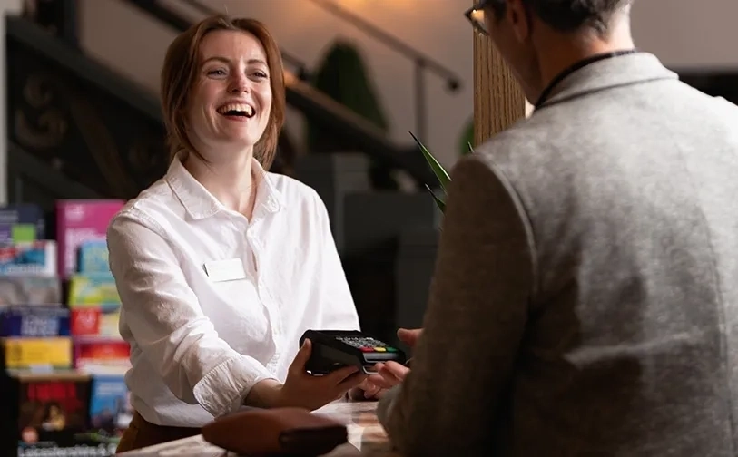 Person hält ein zahlungsterminal einem kunden an einer rezeption entgegen